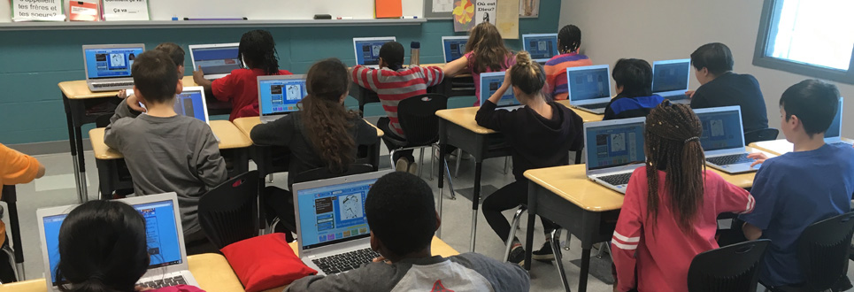 students using laptops in a classroom.
